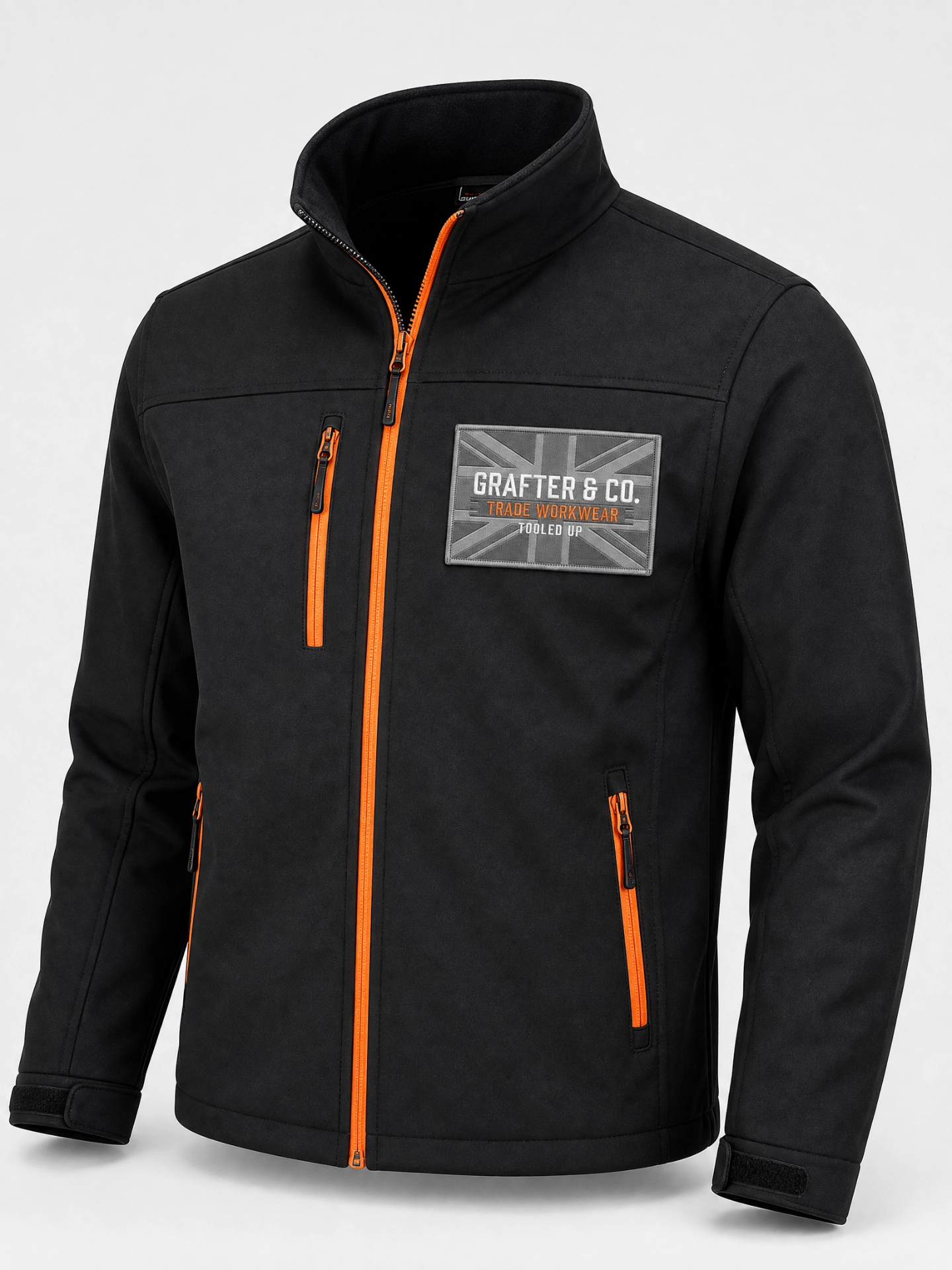 Black Grafter & Co. softshell jacket with orange zips and rectangular union jack chest patch on a plain background