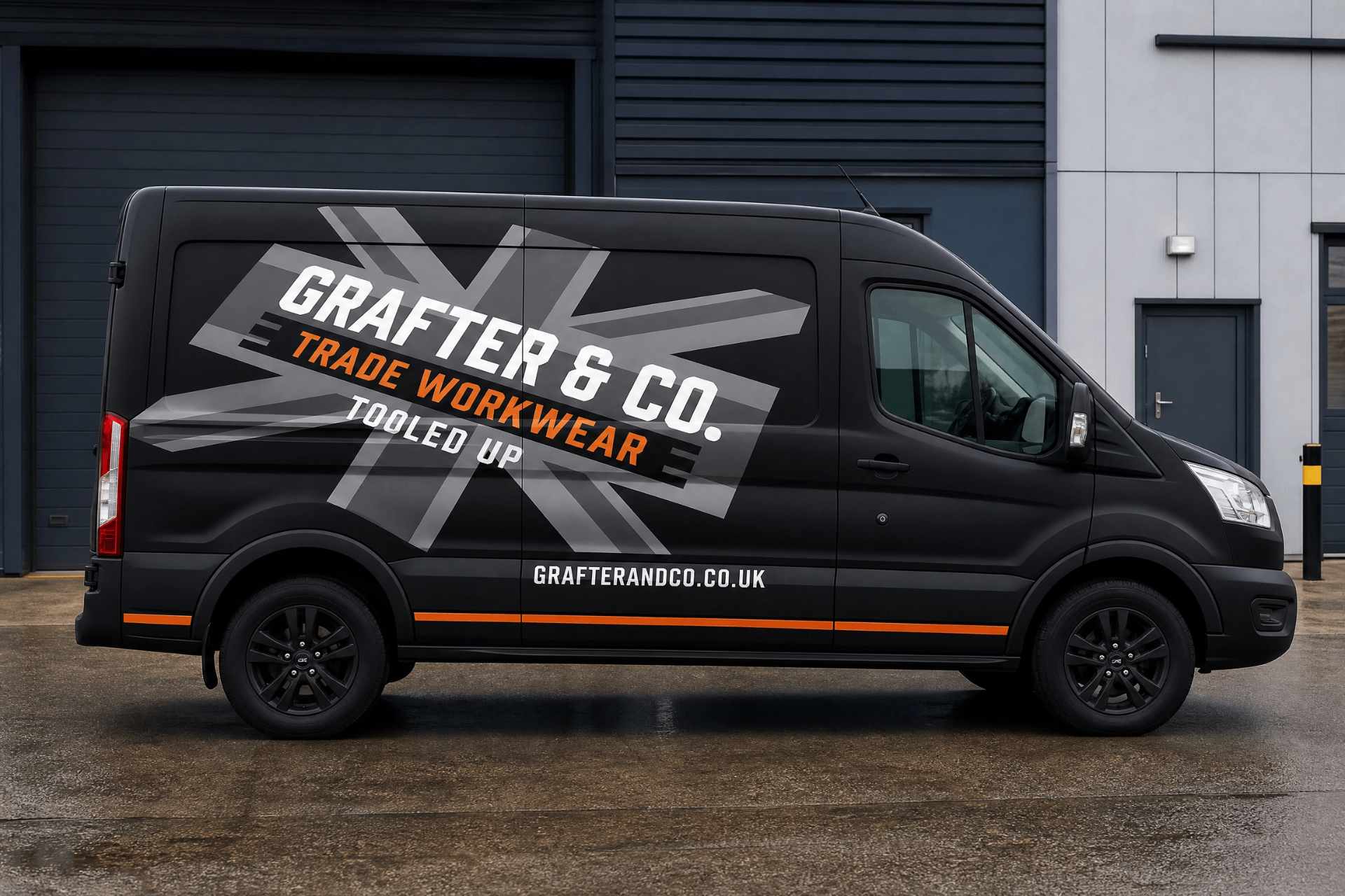 Side profile of a matte black Ford Transit van with the full Grafter & Co. union jack livery, orange stripe and grafterandco.co.uk URL outside an industrial unit